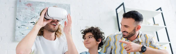 Colpo panoramico di figlio di razza mista guardando il padre omosessuale in cuffia realtà virtuale — Foto stock