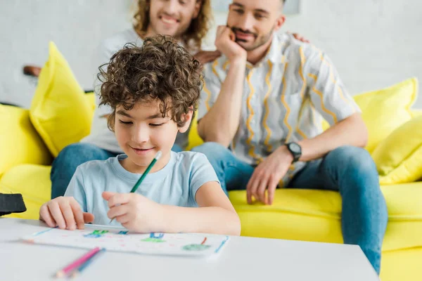 Selective focus of mixed race kid drawing near homosexual parents — Stock Photo