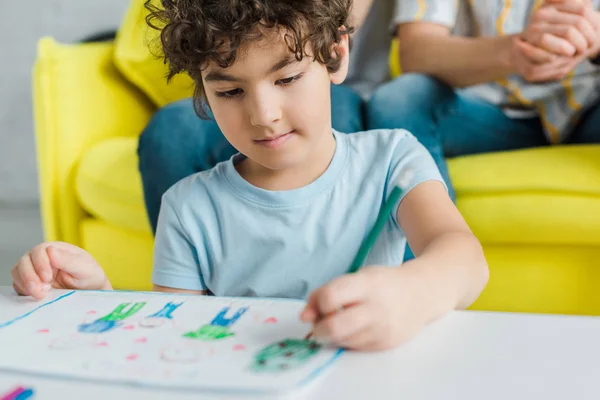 Selective focus of cute mixed race kid drawing near homosexual parents — Stock Photo