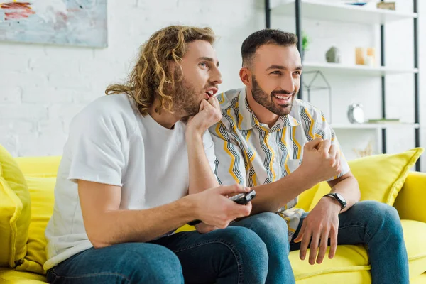 Feliz homosexual hombres viendo tv en sala de estar - foto de stock
