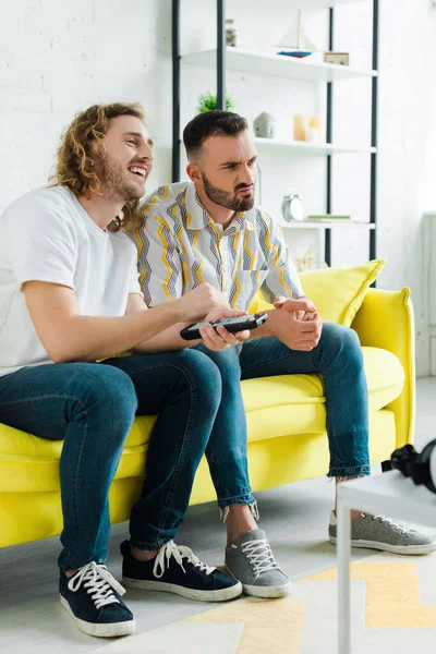 Hommes homosexuels émotionnels regarder la télévision dans le salon — Photo de stock