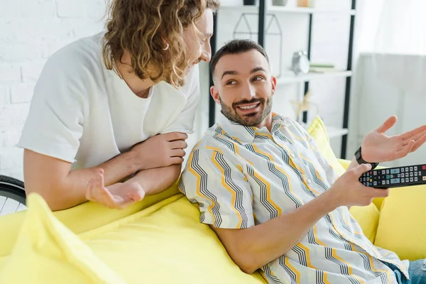 Feliz homossexual homens sorrindo enquanto assistindo tv na sala de estar — Fotografia de Stock