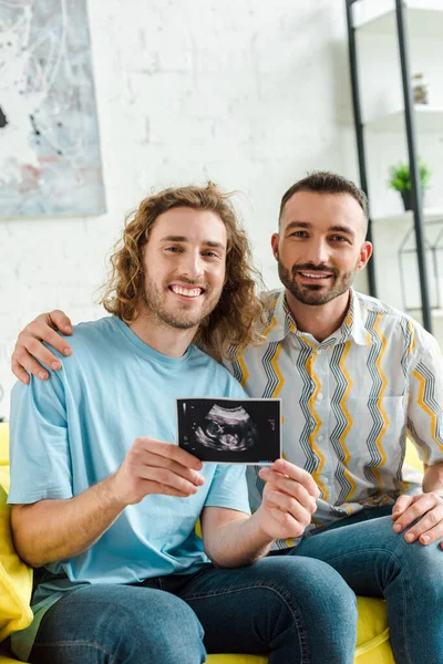 Alegres hombres homosexuales sosteniendo ultrasonido escaneo - foto de stock