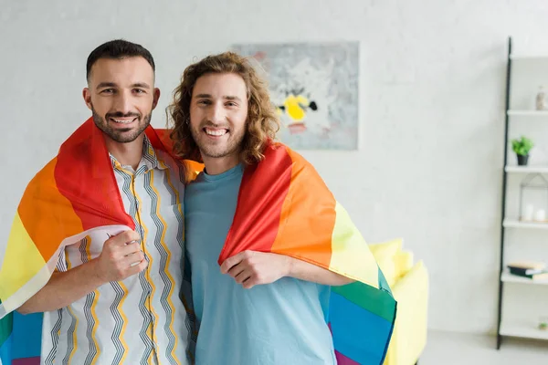 Feliz homosexual hombres sosteniendo lgbt bandera y mirando a la cámara - foto de stock