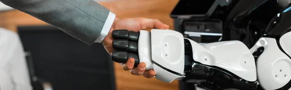 Vista parziale di uomo d'affari e robot che stringe la mano in ufficio, colpo panoramico — Foto stock