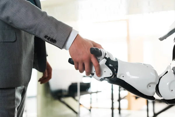 Cropped view of businessman and robot shaking hands in office — Stock Photo