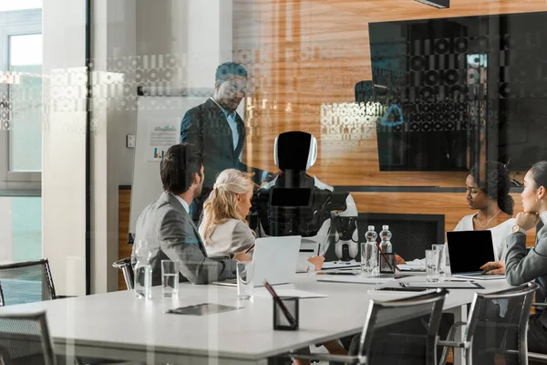 Empresário afro-americano mostrando robô para colegas multiculturais na sala de conferências — Fotografia de Stock