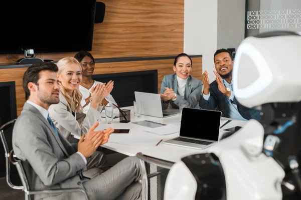 Foyer sélectif des gens d'affaires multiculturels applaudissant tout en regardant robot dans le bureau — Photo de stock