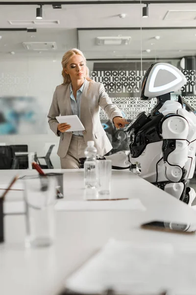 Foyer sélectif de robot attrayant d'exploitation de femme d'affaires tout en tenant la tablette numérique — Photo de stock