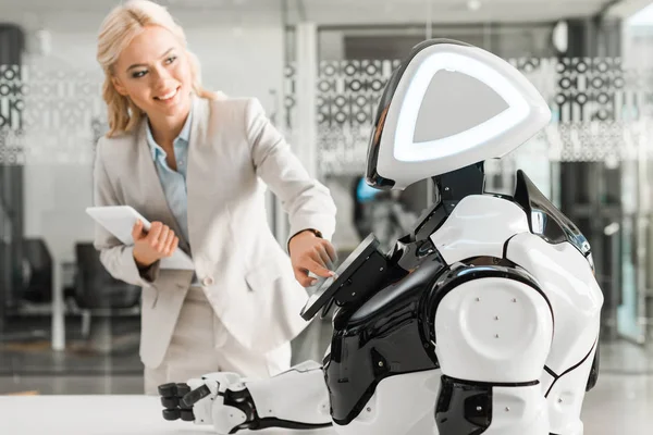 Lächelnde Geschäftsfrau bedient Roboter mit digitalem Tablet — Stockfoto