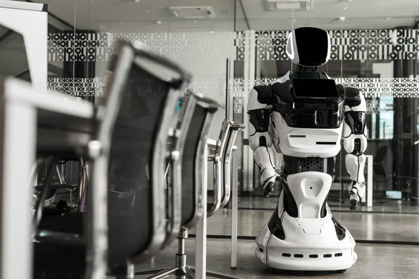 Selective focus of humanoid robot standing in conference hall of modern office — Stock Photo
