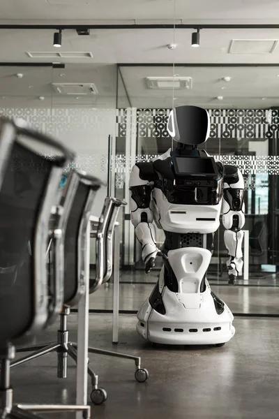 Selective focus of humanoid robot standing in conference hall of modern office — Stock Photo