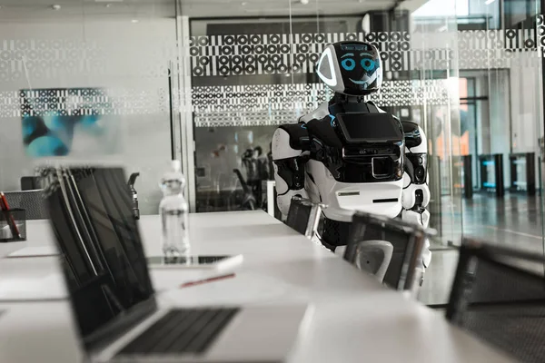 Selektiver Fokus des humanoiden Roboters, der in der Nähe des Schreibtisches im Konferenzsaal steht — Stockfoto