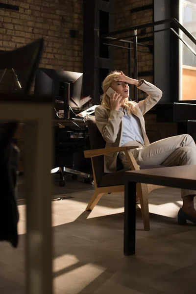 Foco seletivo de mulher de negócios cansada falando no smartphone enquanto sofre de dor de cabeça — Fotografia de Stock