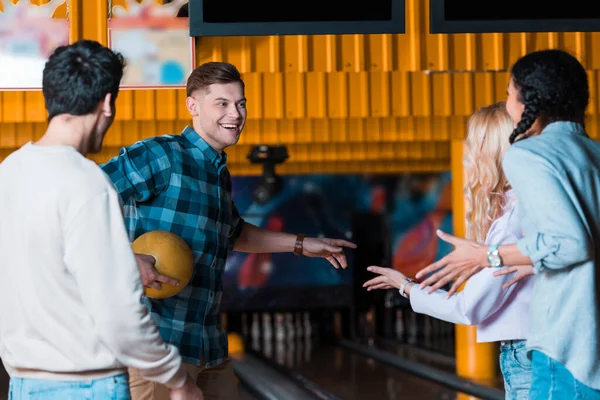 Happy multicultural friends talking and gesturing in bowling club — Stock Photo