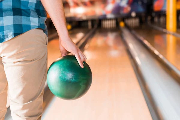 Partial view of young man holding bowling ball near skittle alley — Stock Photo