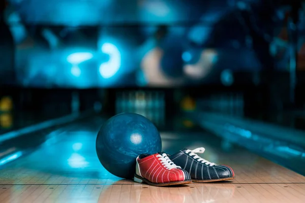 Focus selettivo di scarpe da bowling e palla sulla pista da skittle nel bowling club — Foto stock