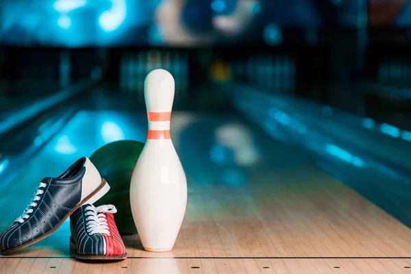 Selective focus of bowling shoes, ball and skittle on bowling alley — Stock Photo