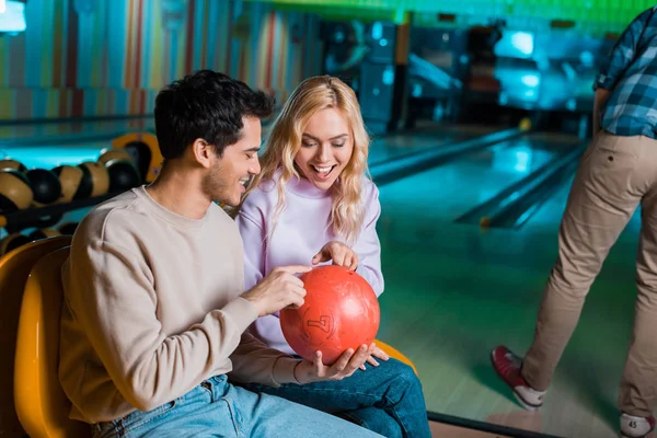 Cheeful homem e mulher olhando para bowilng bola enquanto sentado no clube de boliche — Fotografia de Stock