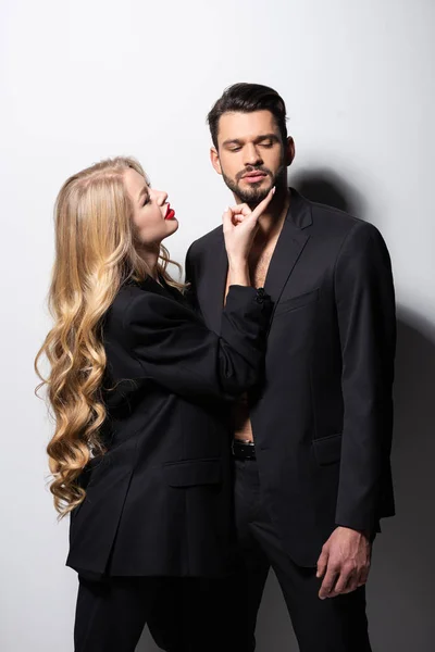 Beautiful young woman touching face of bearded man on white — Stock Photo