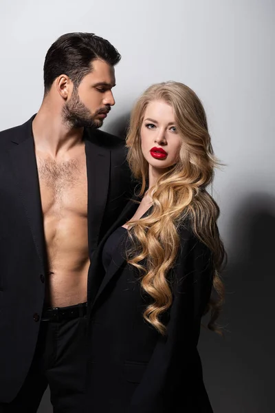 Handsome man looking at attractive and curly girlfriend with red lips on white — Stock Photo