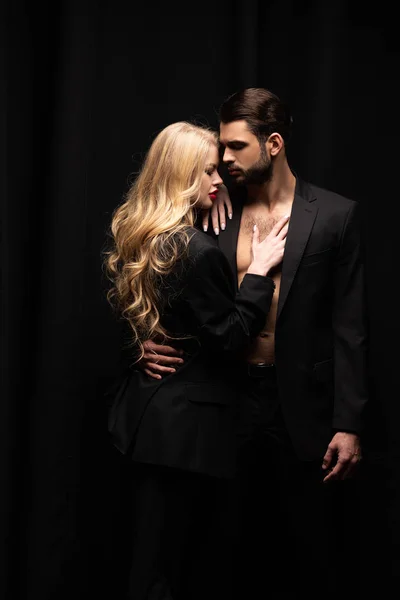 Приваблива жінка обіймає красивого чоловіка ізольовано на чорному — стокове фото