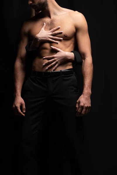 Vista ritagliata di giovane donna toccando uomo sexy isolato su nero — Foto stock