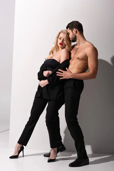 Stylish woman standing with shirtless man on white — Stock Photo