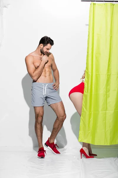 Happy man looking at buttocks of sexy pin up girl standing near shower curtain on white — Stock Photo