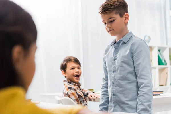 Selective focus of happy schoolkids looking at upset schoolboy, bullying concept — Stock Photo
