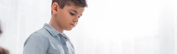 Panoramic shot of upset schoolboy in classroom — Stock Photo