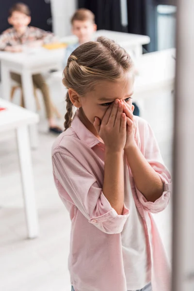 Selective focus of frustrated schoolkid crying near schoolboys, bullying concept — Stock Photo