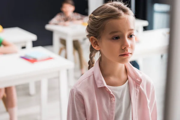 Enfoque selectivo de los escolares frustrados de pie cerca de compañeros de clase, concepto de intimidación - foto de stock