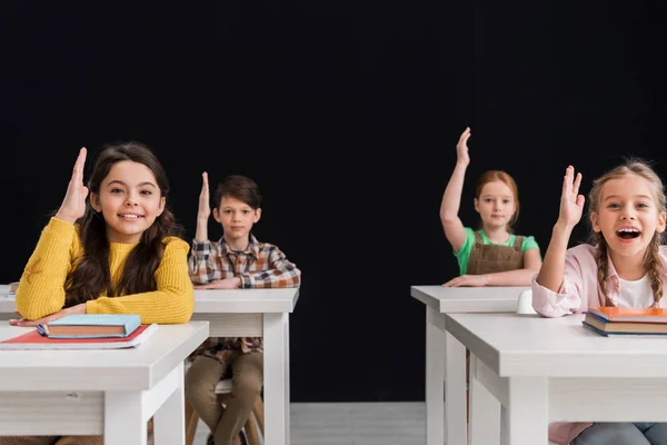 Selektiver Fokus glücklicher Schulkinder mit erhobenen Händen auf Schwarz — Stockfoto