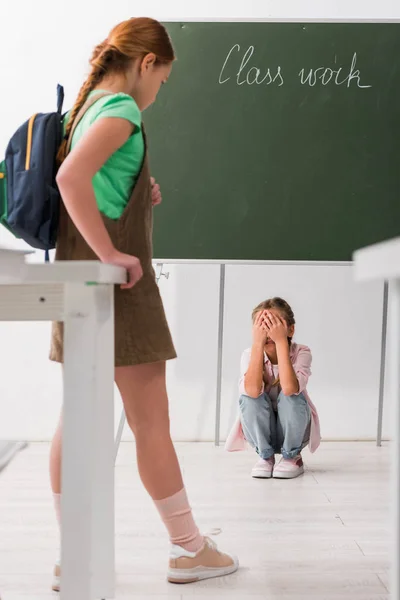 Foco seletivo de estudante olhando para companheiro chorando, conceito de bullying — Fotografia de Stock