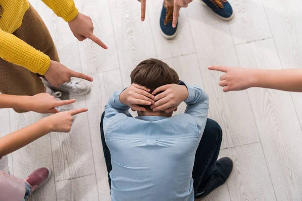 Vista superior de los escolares crueles señalando con los dedos a su compañero de clase acosado — Stock Photo