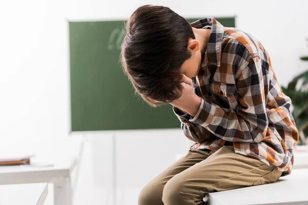 Gemobbter Schüler verdeckt Gesicht, während er im Klassenzimmer weint — Stockfoto