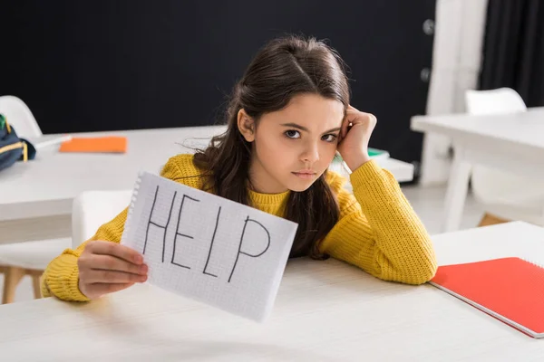 Verärgerte Schülerin hält Papier mit Hilfe von Schriftzügen in der Hand, Mobbingkonzept — Stockfoto