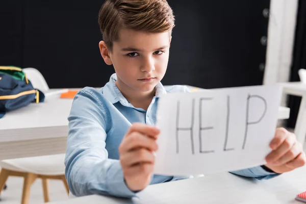 Selective focus of depressed schoolkid holding paper with help lettering, bullying concept — Stock Photo