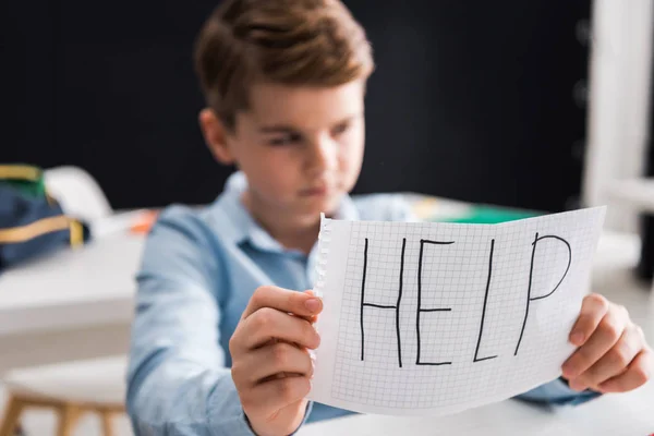 Selective focus of paper with help lettering in hand of upset schoolboy, bullying concept — Stock Photo