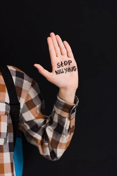 Cropped view of schoolboy with stop bullying lettering on hand isolated on black — Stock Photo