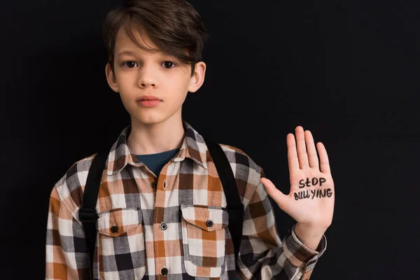 Triste scolaro con stop bullismo lettering a portata di mano isolato su nero — Foto stock