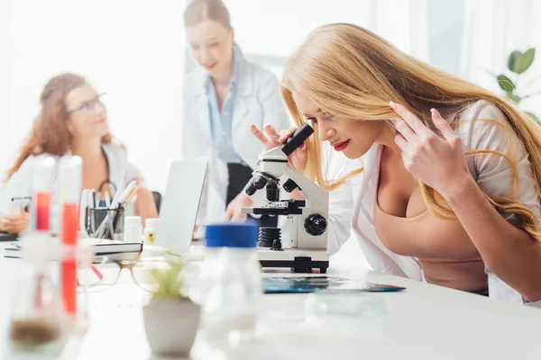 Selective focus of sexy nurse looking through microscope — Stock Photo