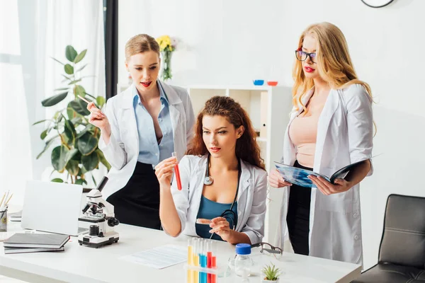 Sexy nurses looking at test tube with sample in laboratory — Stock Photo