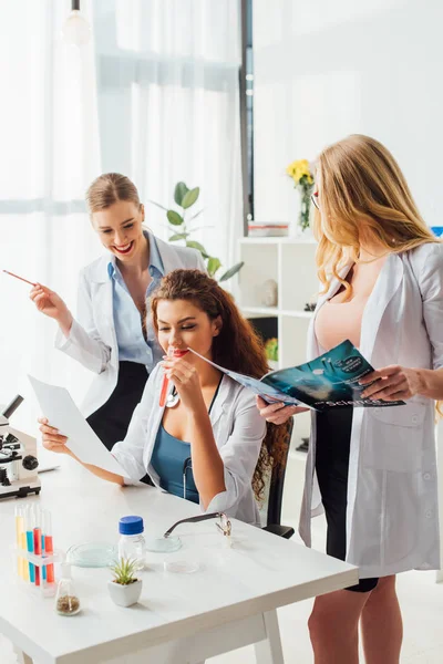 Infirmières heureuses et sexy en manteaux blancs souriant en laboratoire — Photo de stock