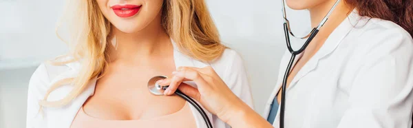 Plan panoramique de sexy infirmière examen jeune femme avec gros seins — Photo de stock