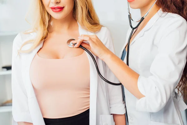 Cropped view of sexy nurse examining young woman with big breast — Stock Photo