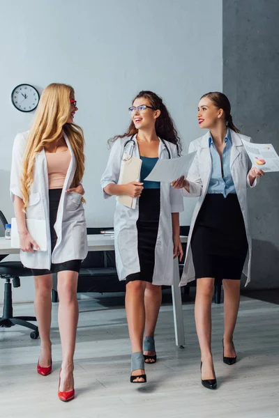 Happy and sexy nurses in white coats walking in clinic — Stock Photo