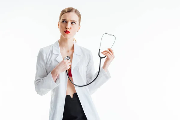 Sexy enfermera en blanco abrigo celebración estetoscopio aislado en blanco - foto de stock