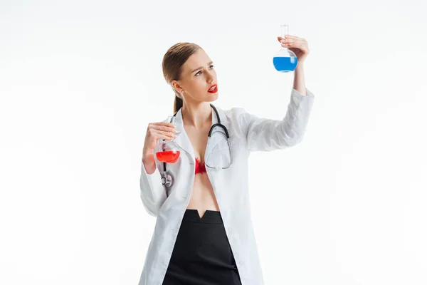 Sexy nurse holding flasks with red and blue liquid isolated on white — Stock Photo